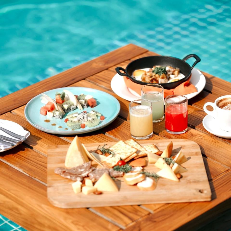 Breakfast spread with fruits and drinks on a poolside table in Azure Pool Deck Bistro & Bar at The Terraces Resort & Spa