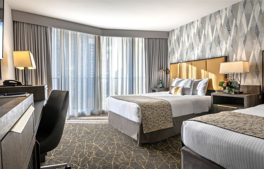 Two double beds featuring gold headboards by a desk under large windows in Accessible Executive Room at Warwick Seattle