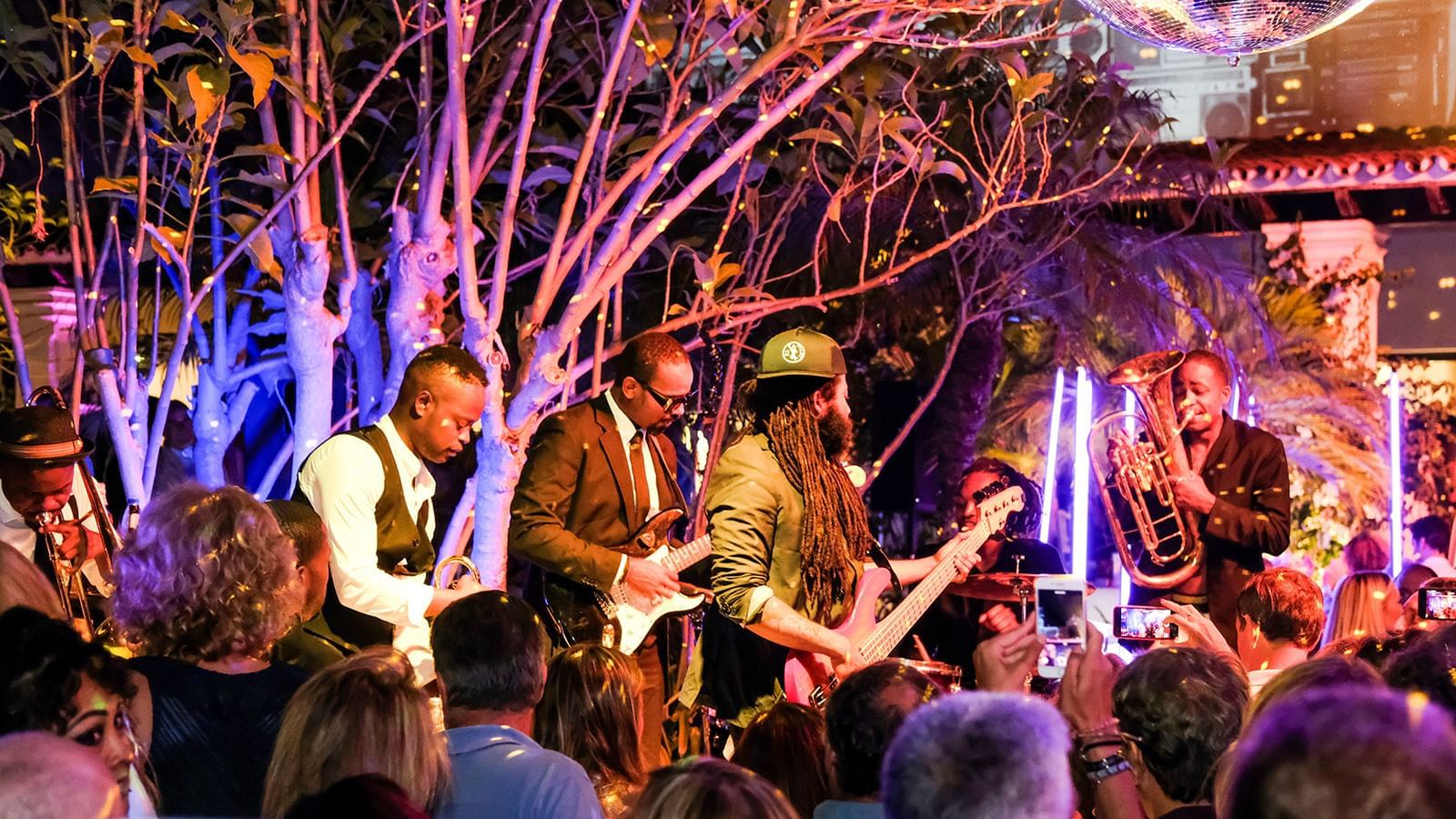 Marbella Club live band performing at night under purple lights, with a crowd of guests watching