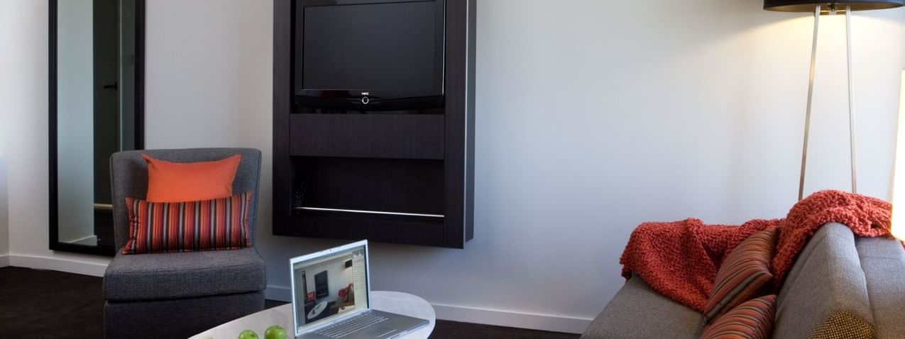 TV lounge with plush seating in Deluxe Suite at Novotel Sydney International Airport