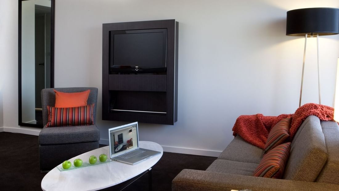 TV lounge with plush seating in Deluxe Suite at Novotel Sydney International Airport