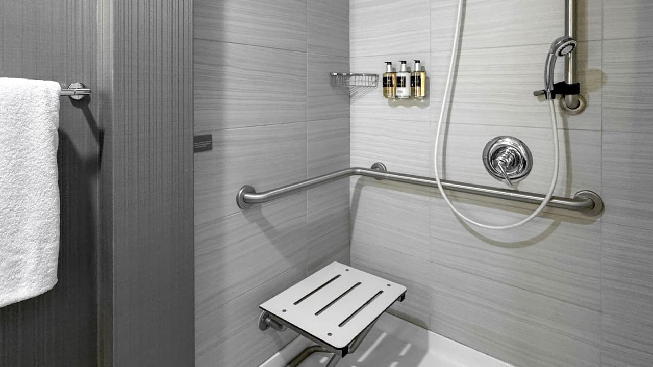 A bathroom with a shower, grab bars, and a shower seat.