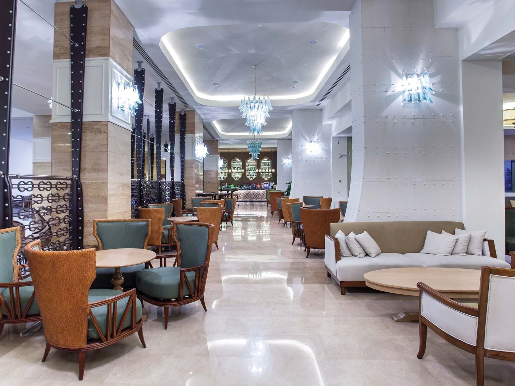 Dining tables arranged with cozy chairs in Caprice Lobby Bar at Titanic Deluxe Lara