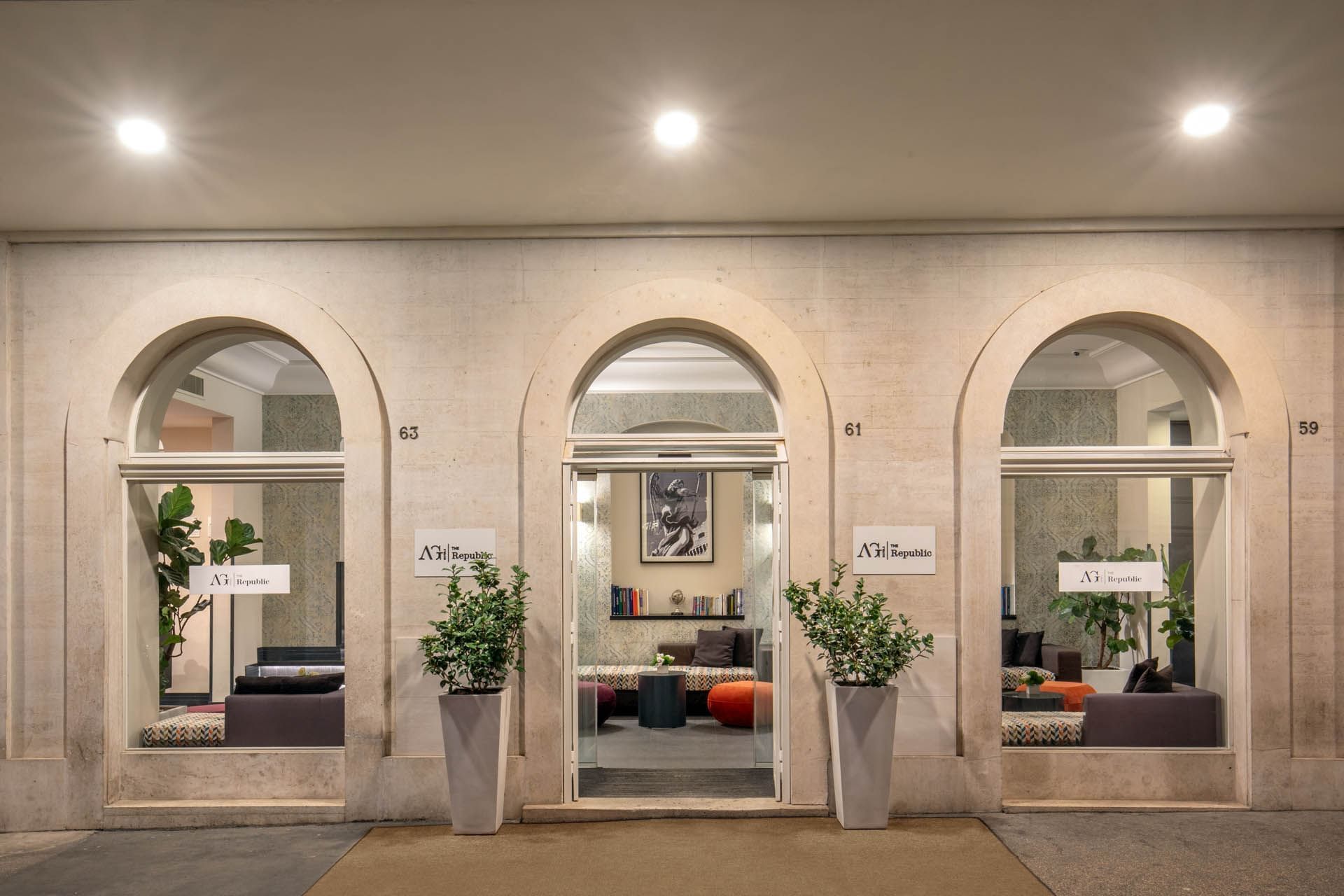 Elegant entrance of The Republic Hotel with arched windows, showcasing a stylish lobby filled with colorful cushions.