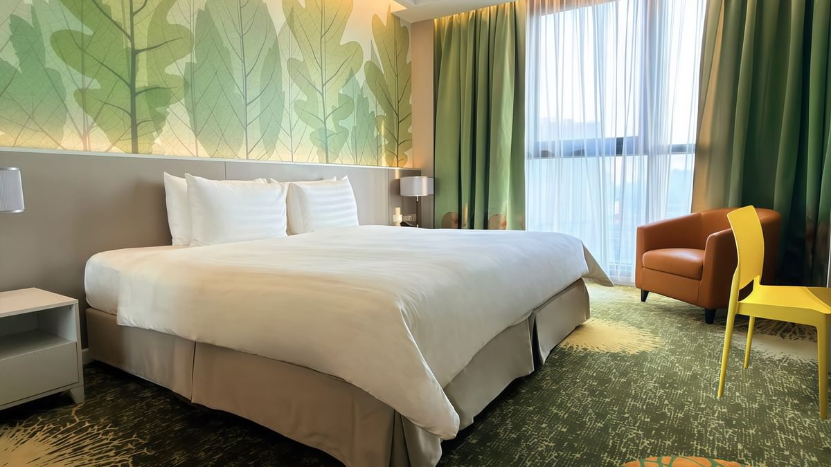 Deluxe Plus King Room with a large bed, chairs, and scenic window at Sunway Velocity Hotel in Kuala Lumpur.