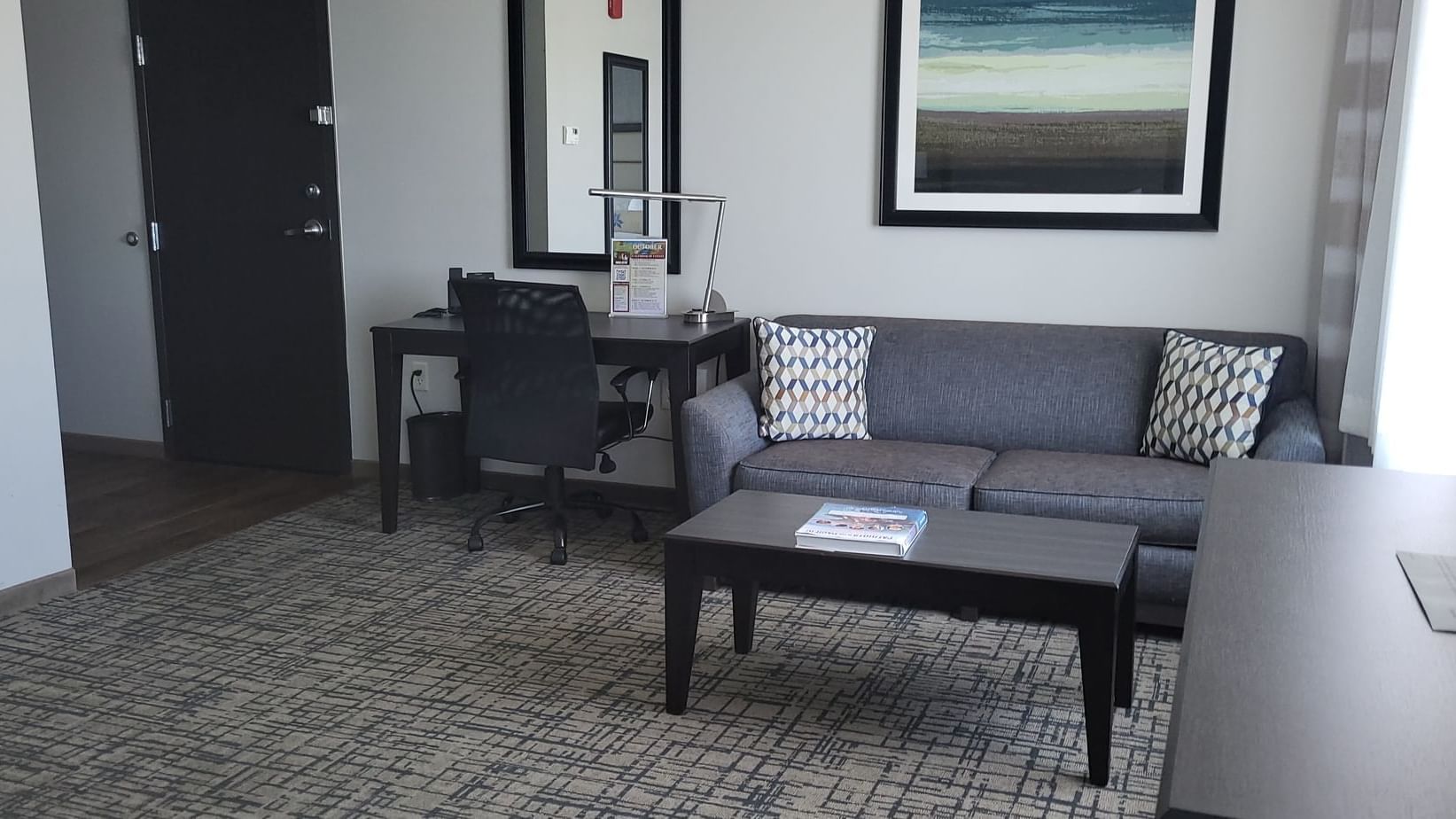 Gray couch with pattered pillows and a word desk beside it in King Studio Balcony at Shangri-La Monkey Island