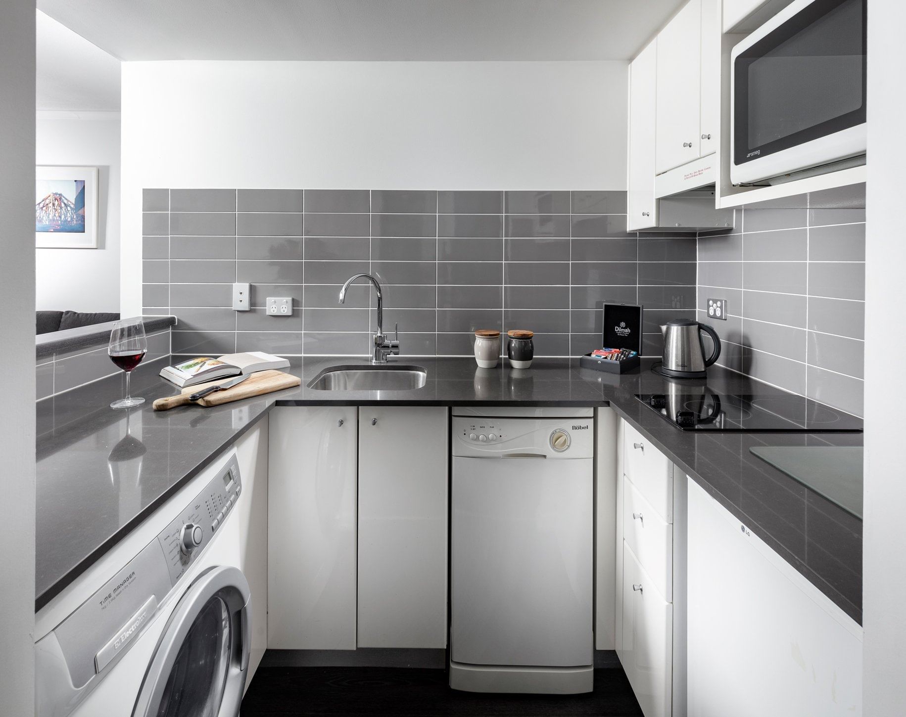 Kitchenette with a washing machine, dishwasher, cooktop, and microwave in One Bedroom Apartment at The Sebel Brisbane