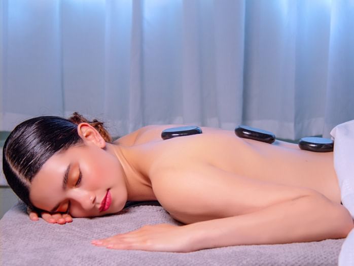 Woman on a massage bed with hot stones in Free Spirit Botanical Spa at Huntingdon Manor