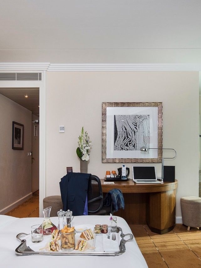 Room Service featuring a work desk under a picture, by an armchair near large windows at Warwick Geneva