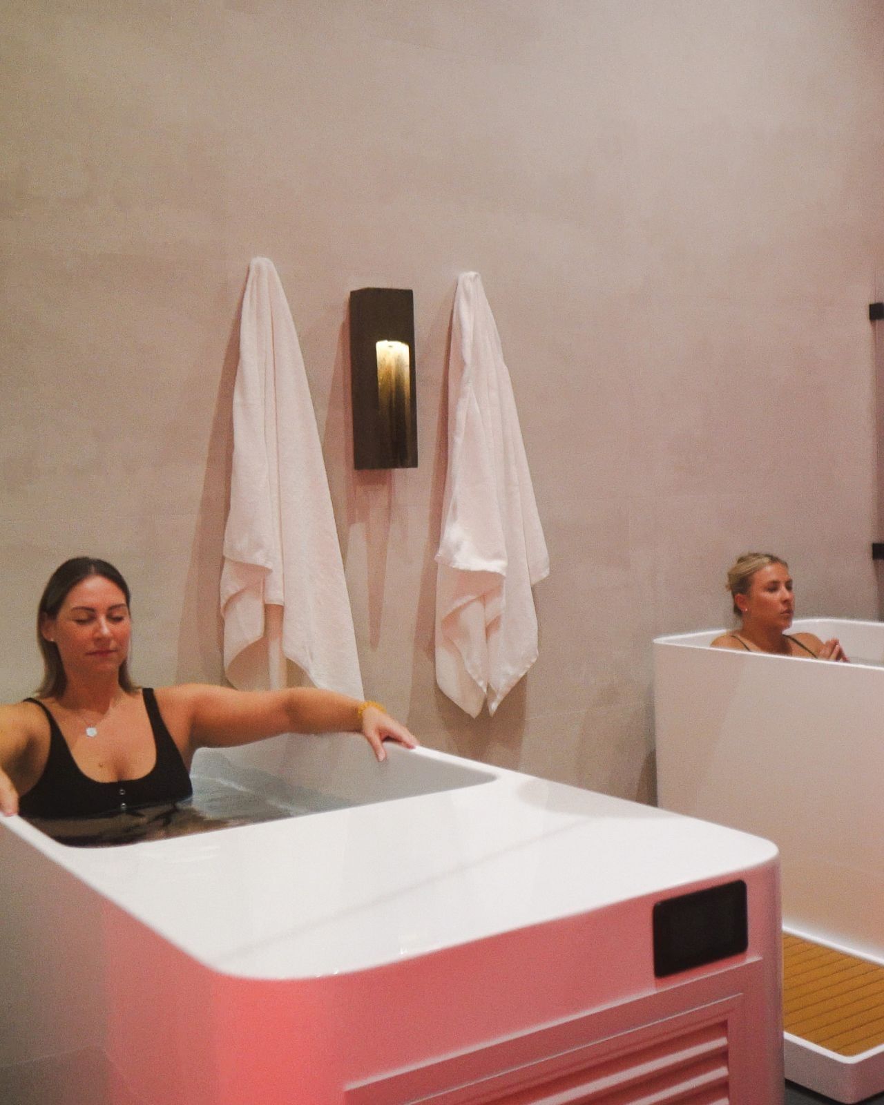 Two guests relaxing in white cold plunge tubs