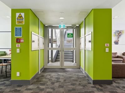 Green corridor with exit sign and seating area at Student Living Auckland Anzac.