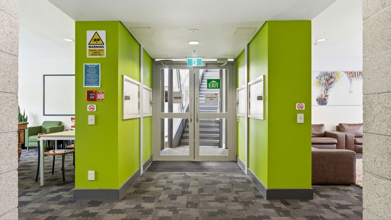 Green corridor with exit sign and seating area at Student Living Auckland Anzac.