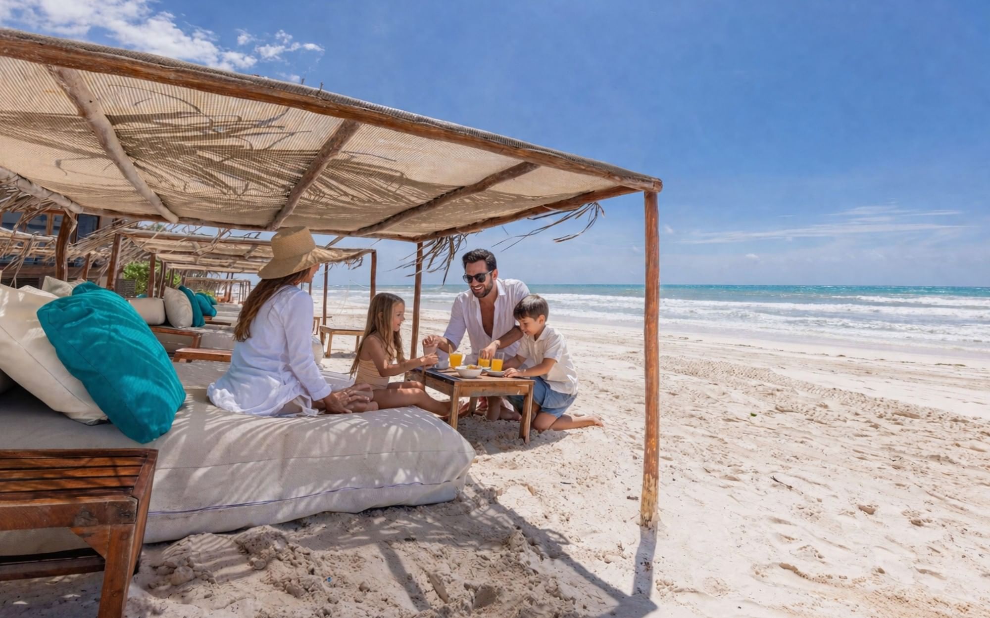 A family gathered around a table beneath a shaded beach bed at La Zebra.
