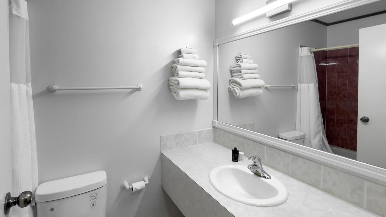 bathroom with bathtub, sink, mirror and folded towels at Coast Whitecourt Hotel
