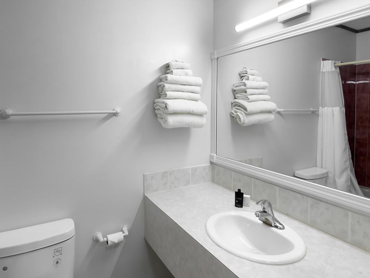 Bright bathroom with a bathtub and shower, sink, mirror and folded towels