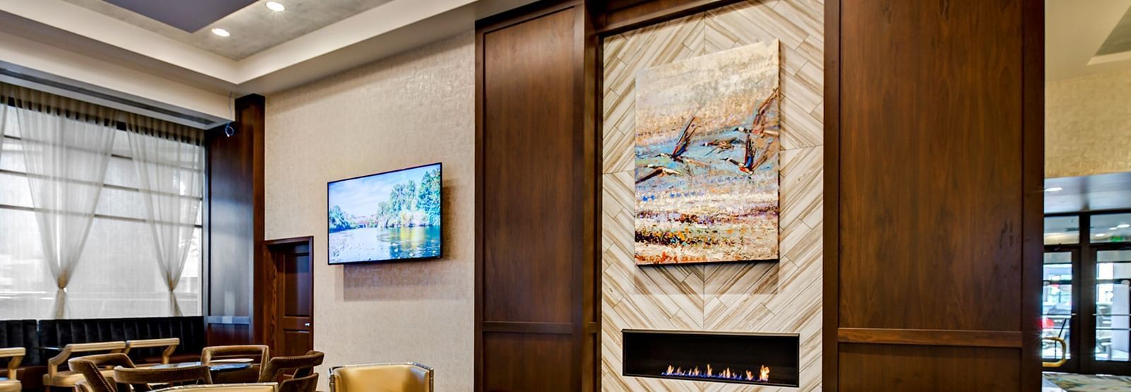 A wall-mounted TV in a lobby area at The Grove Hotel