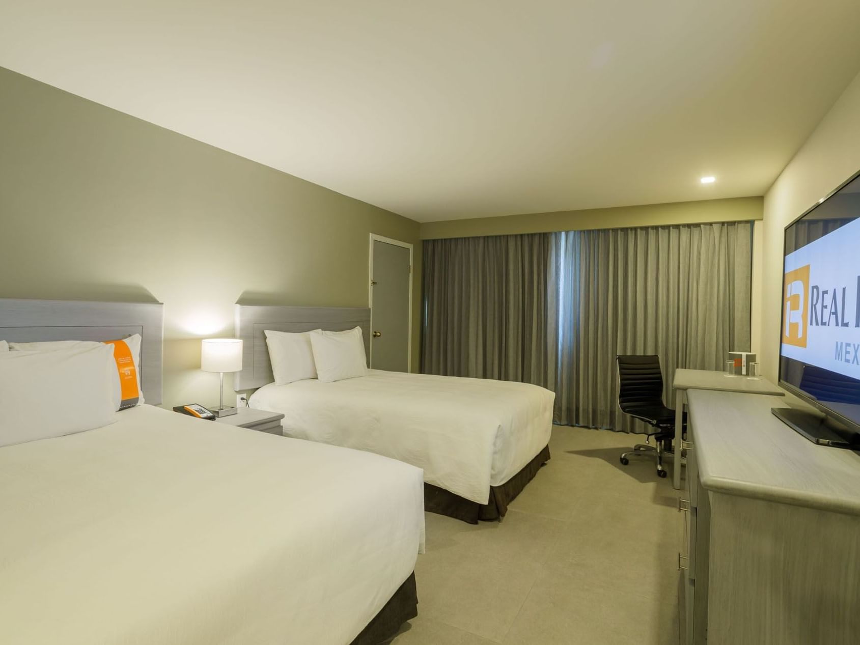 2 Double Deluxe Superior bedroom featuring a large flat-screen TV and a functional work desk area at Real Inn Mexicali