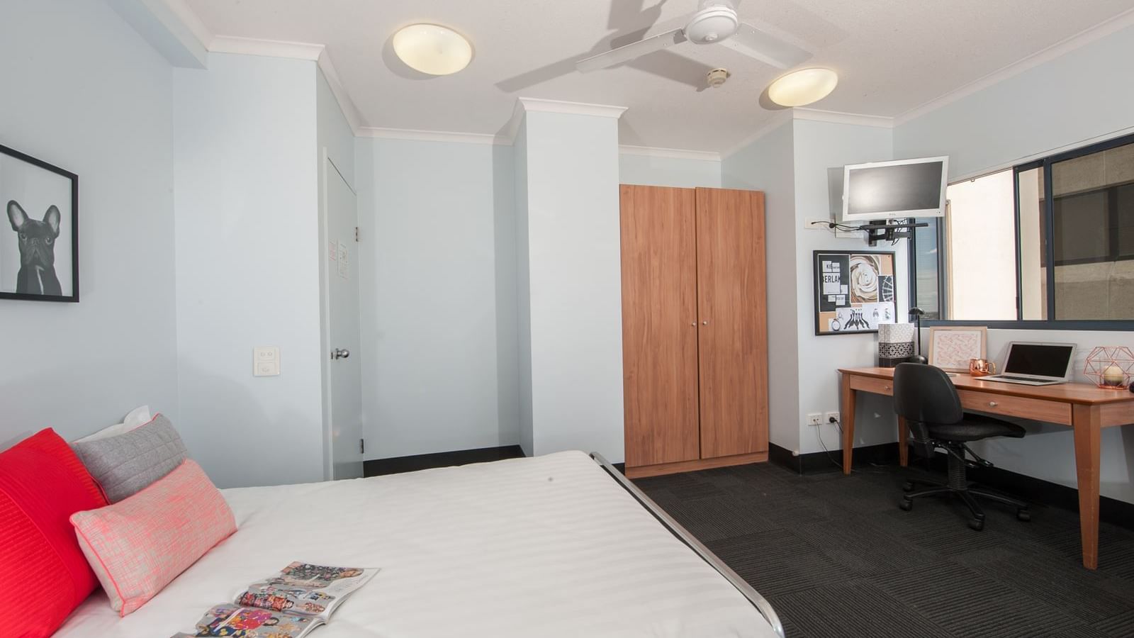 Modern student accommodation room with bed, wooden wardrobe, study desk, and ceiling fan at StudentLiving - on Margaret
