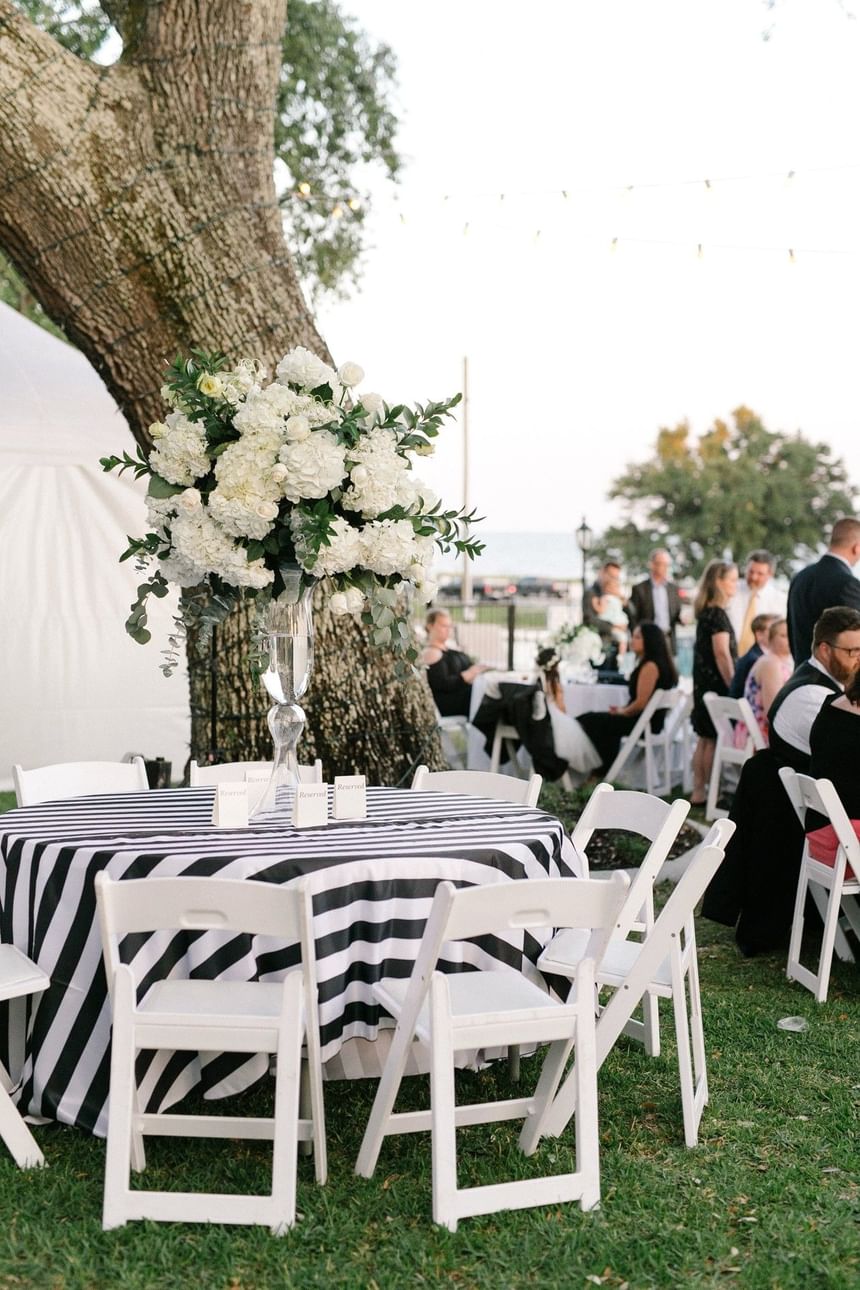 Outdoor reception area featuring white folding chairs and string lights at The White House Hotel on a sunny day