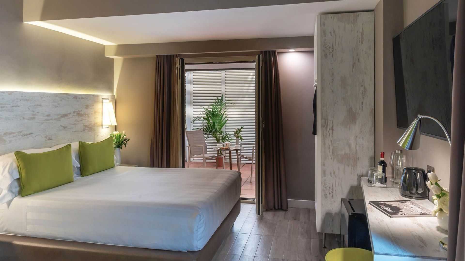 Cozy Deluxe Apartment at The Guardian Hotel with a large bed, greenery, private patio, modern decor, and a workstation