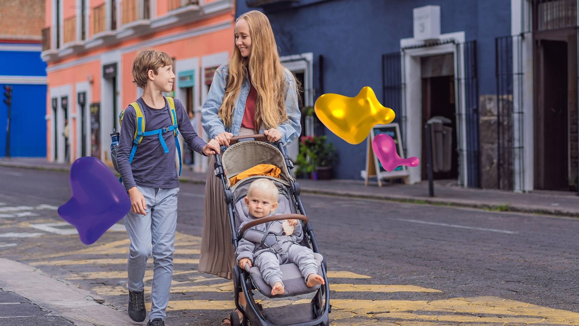 A woman pushes a baby in a stroller while a young boy walks alongside on a colorful street near Quinta Real Puebla