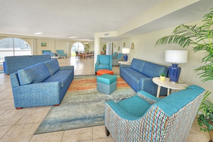 A hotel lobby with blue sofas, armchairs, and a plant