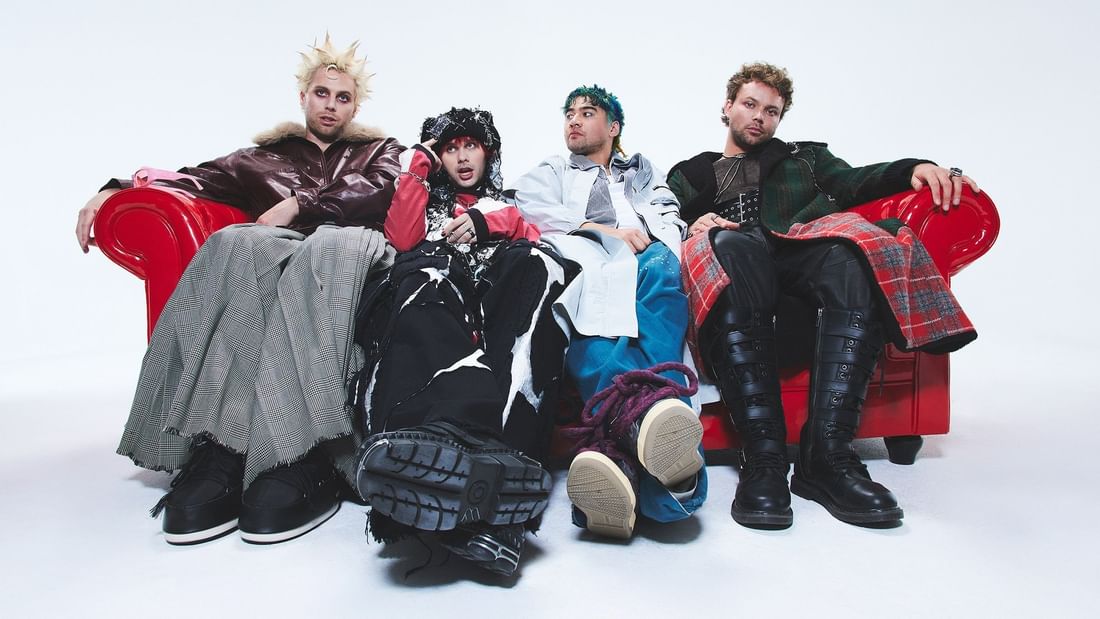 Four musicians seated on red couch promoting 5 Seconds of Summer – EVERYONE’S A STAR! World Tour.