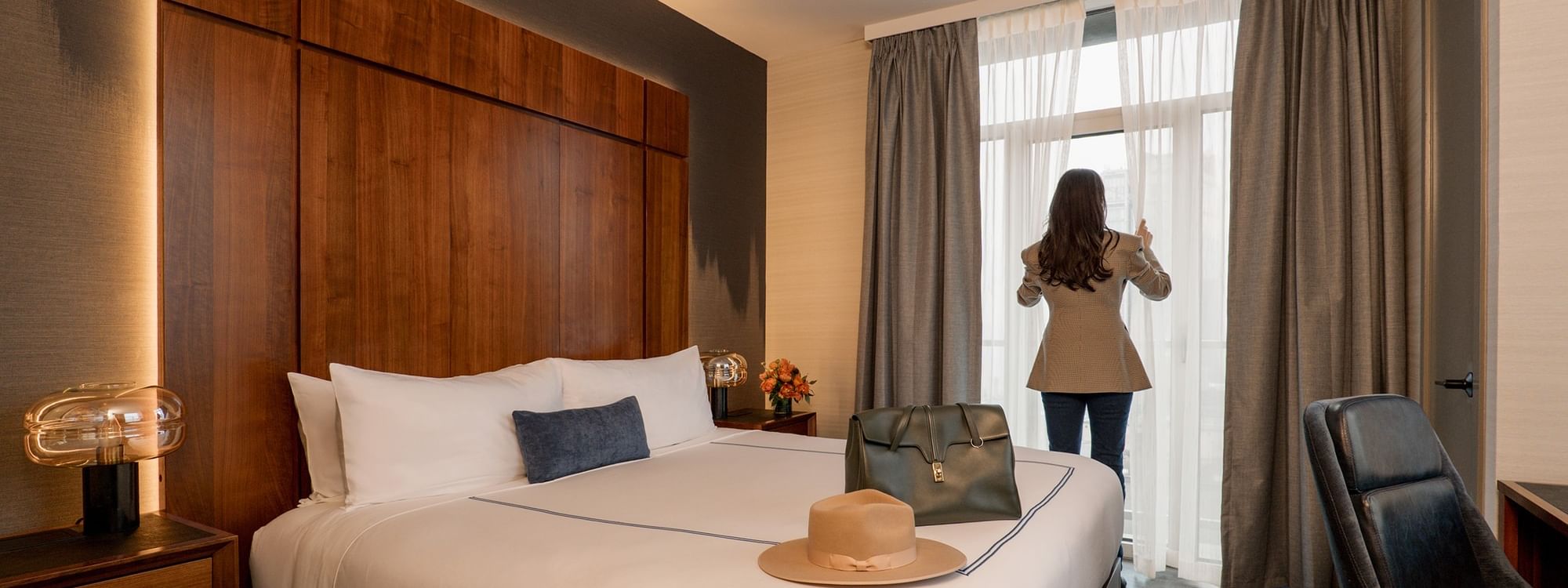 Woman standing at window in the Two-Bedroom Gansevoort Suite at Gansevoort Meatpacking NYC in New York.