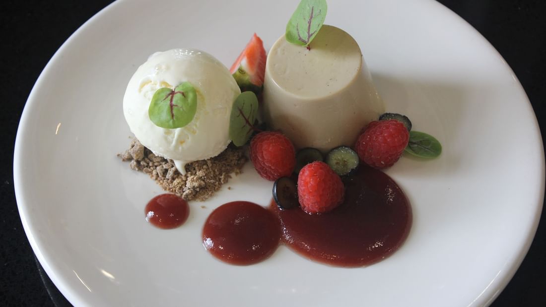 White plate with a dessert and berries showcasing Karinya’s refreshed menu.