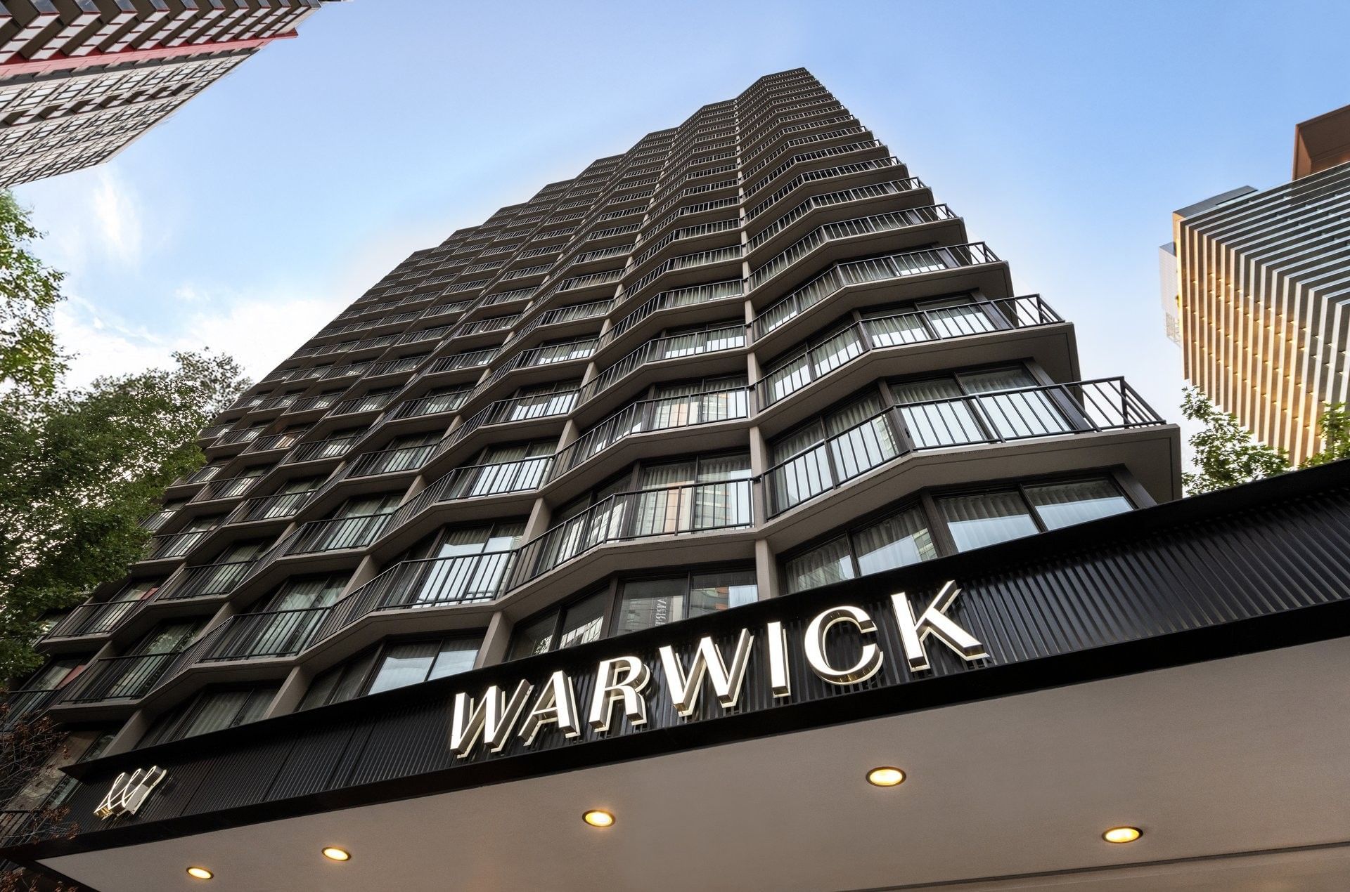 The Warwick Seattle hotel entrance featuring a large black sign under balcony windows