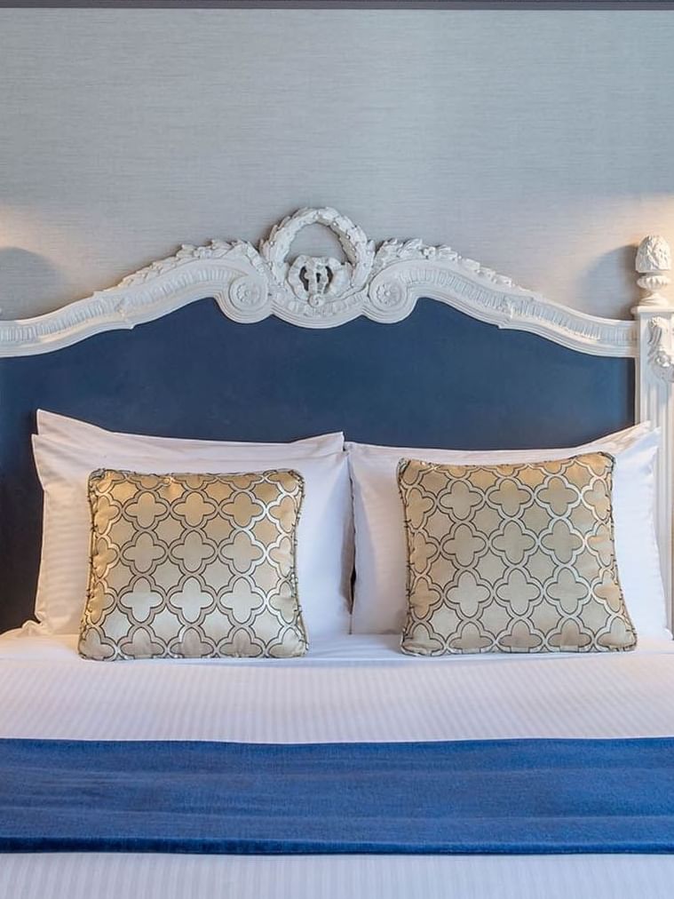 Blue headboard by colorful flowers on nightstands in Accessible Executive Front Suite at Warwick San Francisco