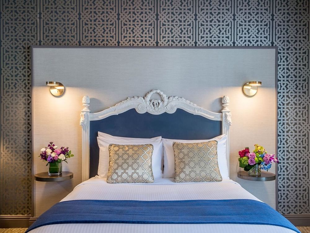 Blue headboard by colorful flowers on nightstands in Accessible Executive Front Suite at Warwick San Francisco