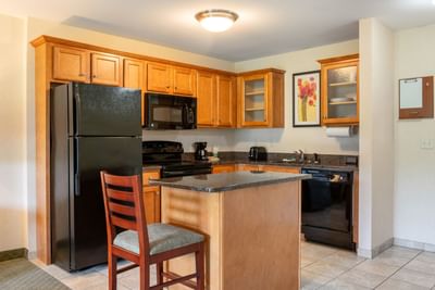 Modern kitchen with wooden cabinets in Queen Deluxe Suite at White River Inn and Suites, featuring places to stay in Vermont