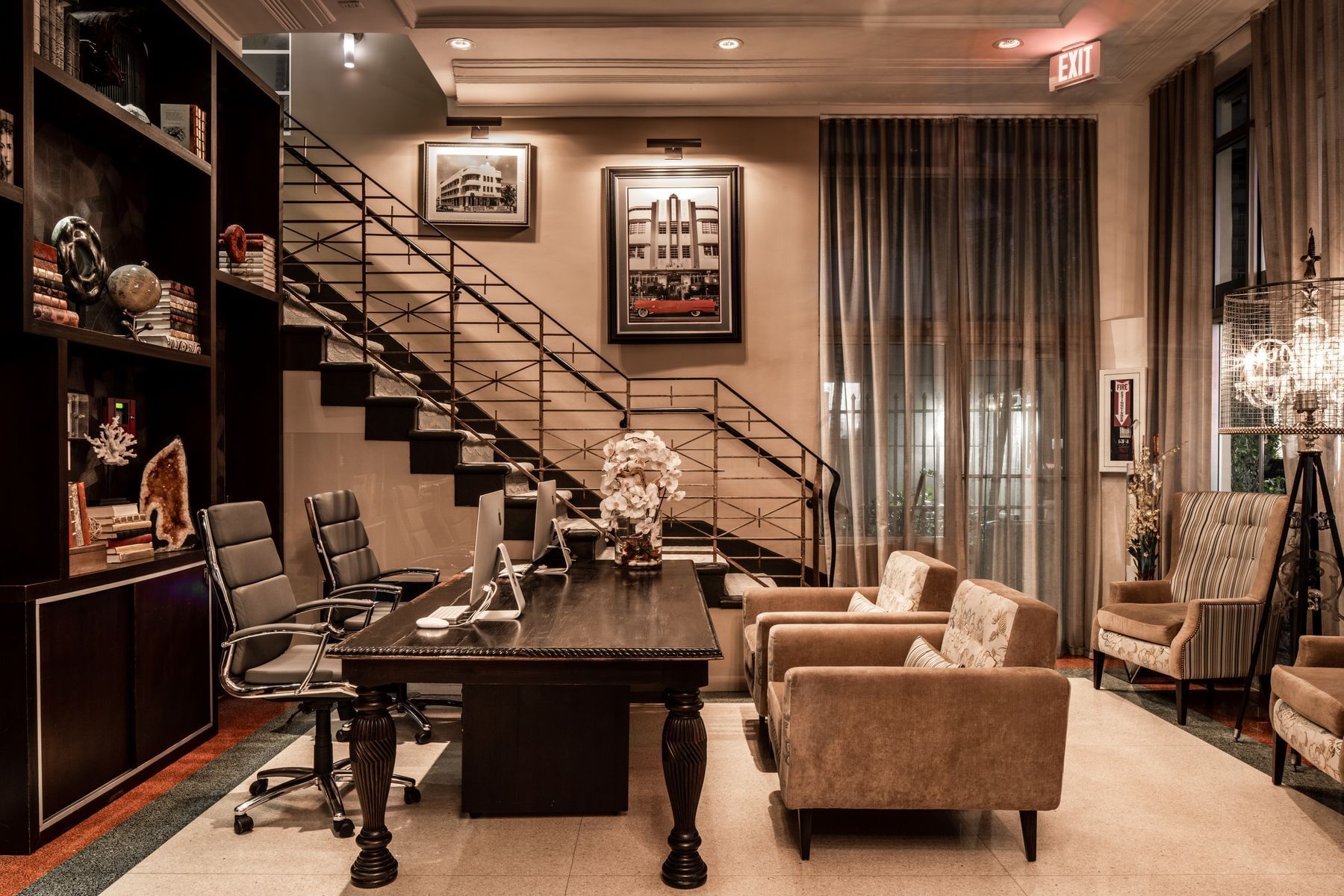 A luxurious lobby with a large desk, comfortable seating, and a staircase leading up to another floor.
