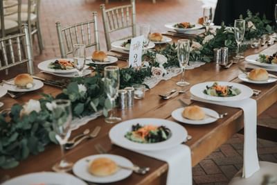 Elegant wooden banquet table with salads, dinner rolls, and eucalyptus centerpiece at Aramark Chauncey Conference Center