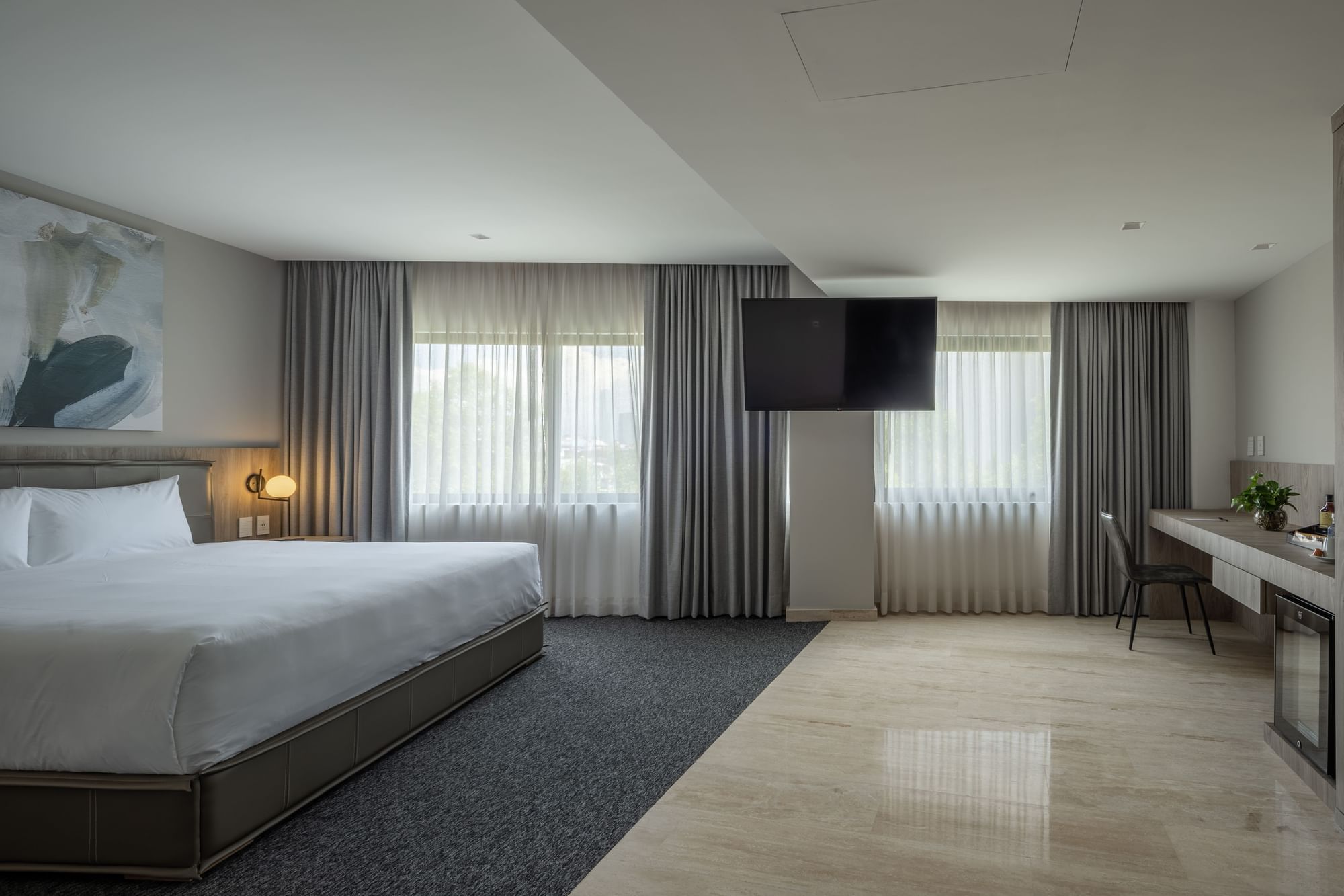 Elegant hotel room with large bed, modern decor, and a workspace at Elements by Marquis