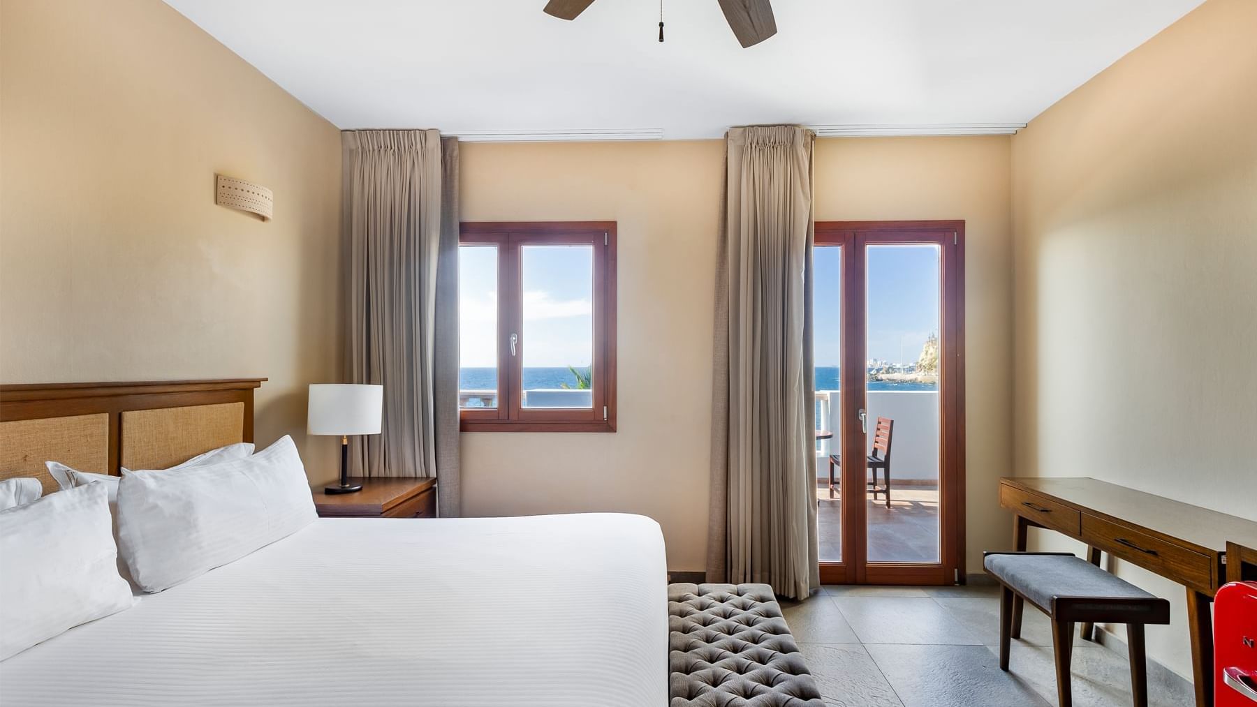 Room featuring a large bed and a balcony with an ocean view at the Curamoria Collection