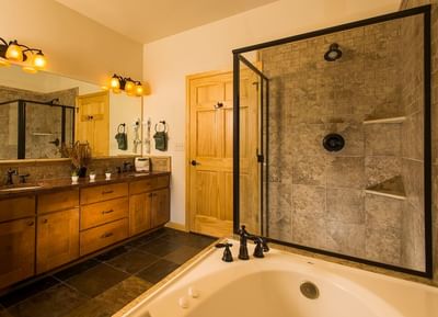 A luxurious bathroom at The Stanley Hotel with a large soaking tub and a spacious walk-in shower with stone tile