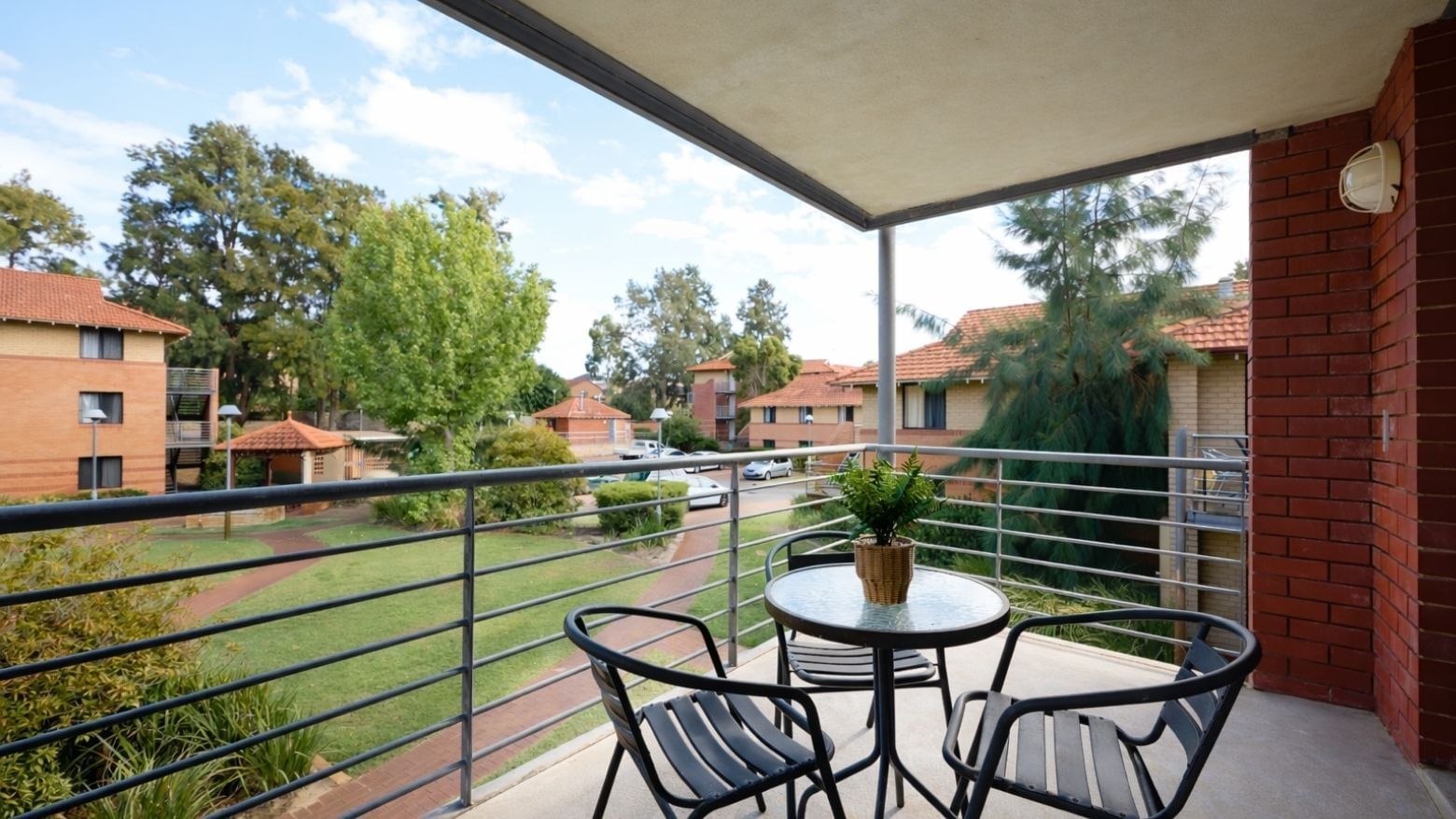 Outdoor balcony with table, chairs, and potted plant at UniLodge at Curtin University - Erica Underwood House.