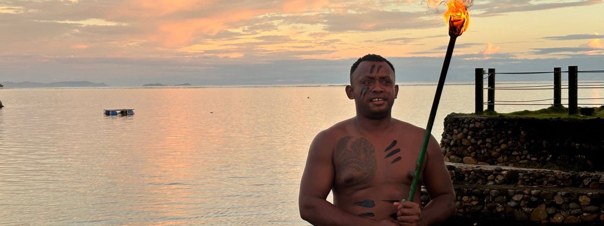 Man with torch at sunset by the ocean at Warwick Fiji Resort and Spa, Korolevu