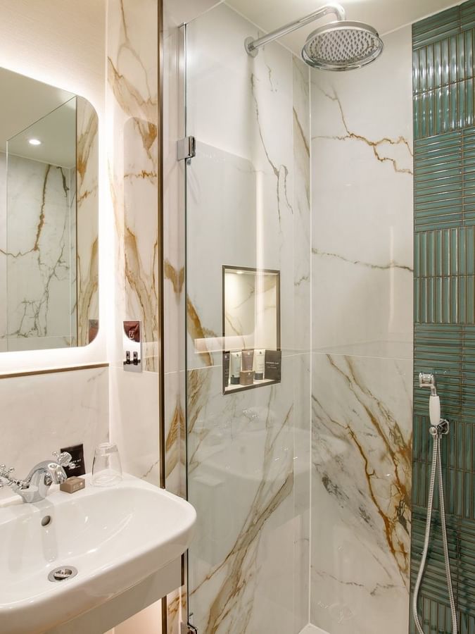 Modern bathroom with marble and teal tiles, glass shower, and sink at The Capital Hotel, Apartments & Townhouse