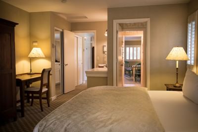 Wide shot of bed and desk with view of the bathroom and other ro