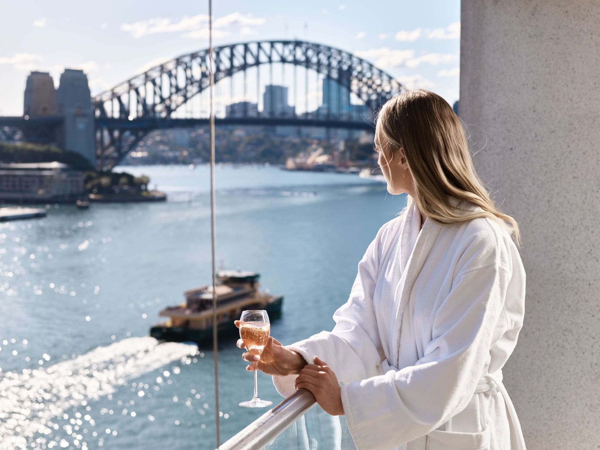 A woman looking at Sydney Harbour Bridge through balcony at Pullman Quay Grand Sydney