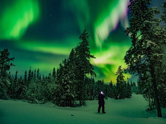 A man stands and watches the northern lights in Canada in winter