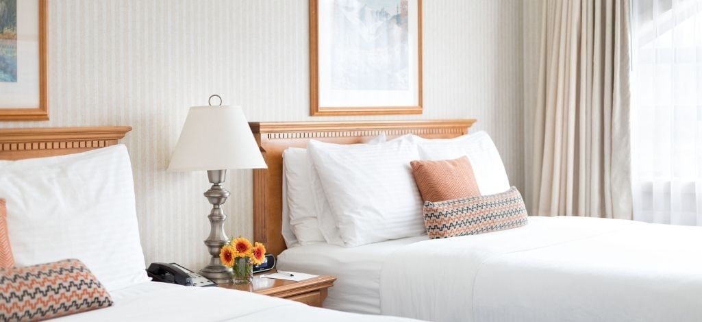 Bright guest room at The Listel Hotel Whistler with two beds and a large window.