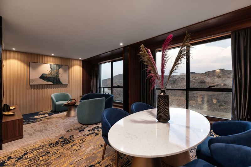 Lounge and dining table by the window with hillside view in the Royal Suite at Warwick Al Taif Hotel
