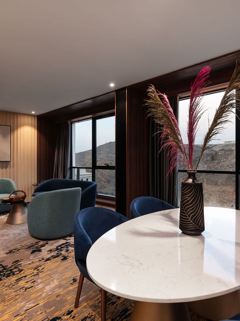 Lounge and dining table by the window with hillside view in the Royal Suite at Warwick Al Taif Hotel