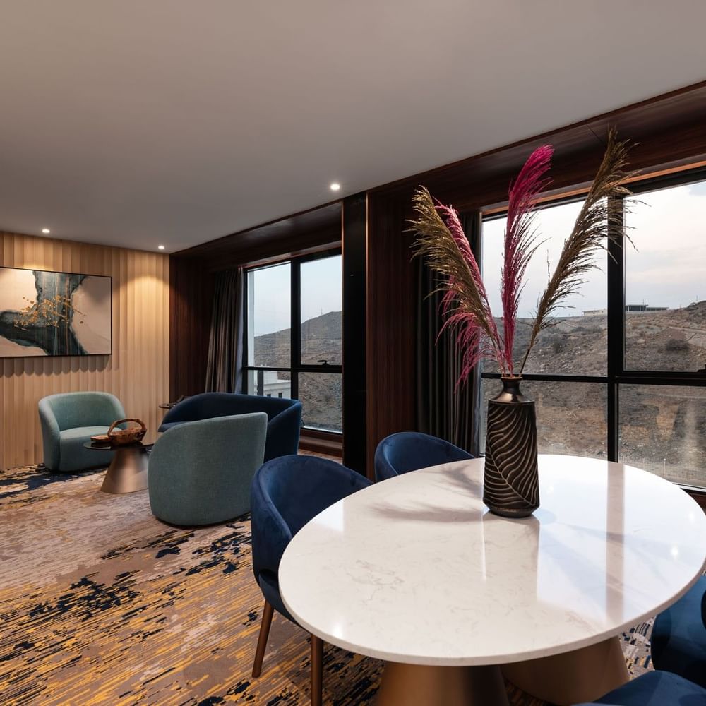 Lounge and dining table by the window with hillside view in the Royal Suite at Warwick Al Taif Hotel