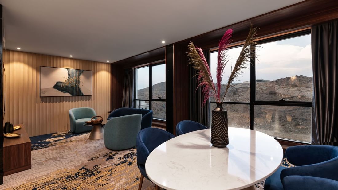 Lounge and dining table by the window with hillside view in the Royal Suite at Warwick Al Taif Hotel