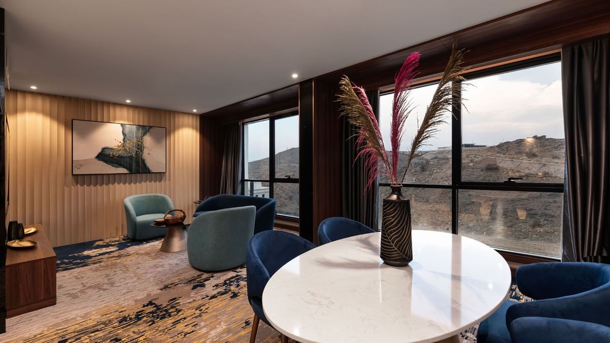 Lounge and dining table by the window with hillside view in the Royal Suite at Warwick Al Taif Hotel